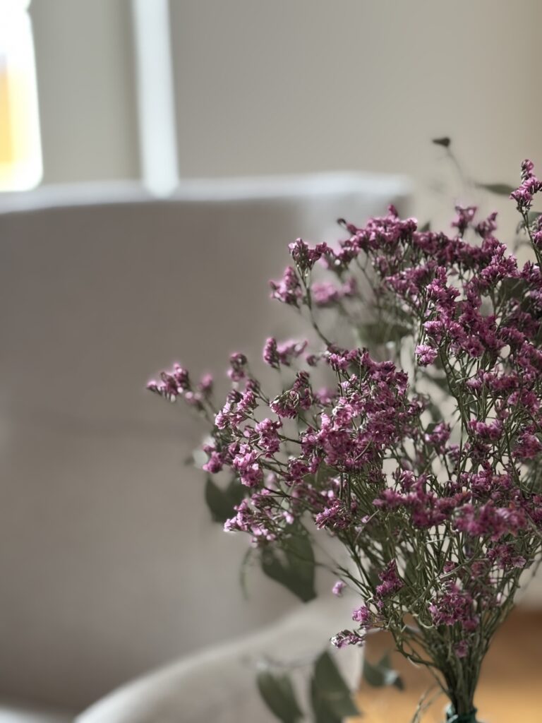 lila Blumen vor beigem Sessel