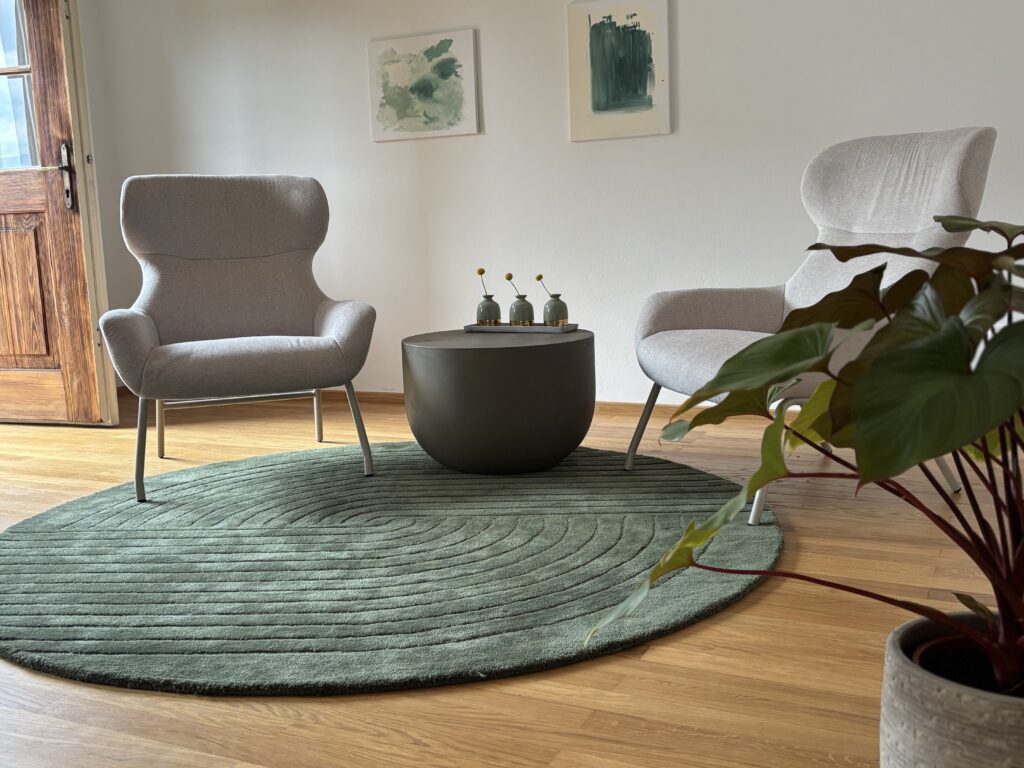 zwei Beige Sessel auf dunkel grünem Teppich