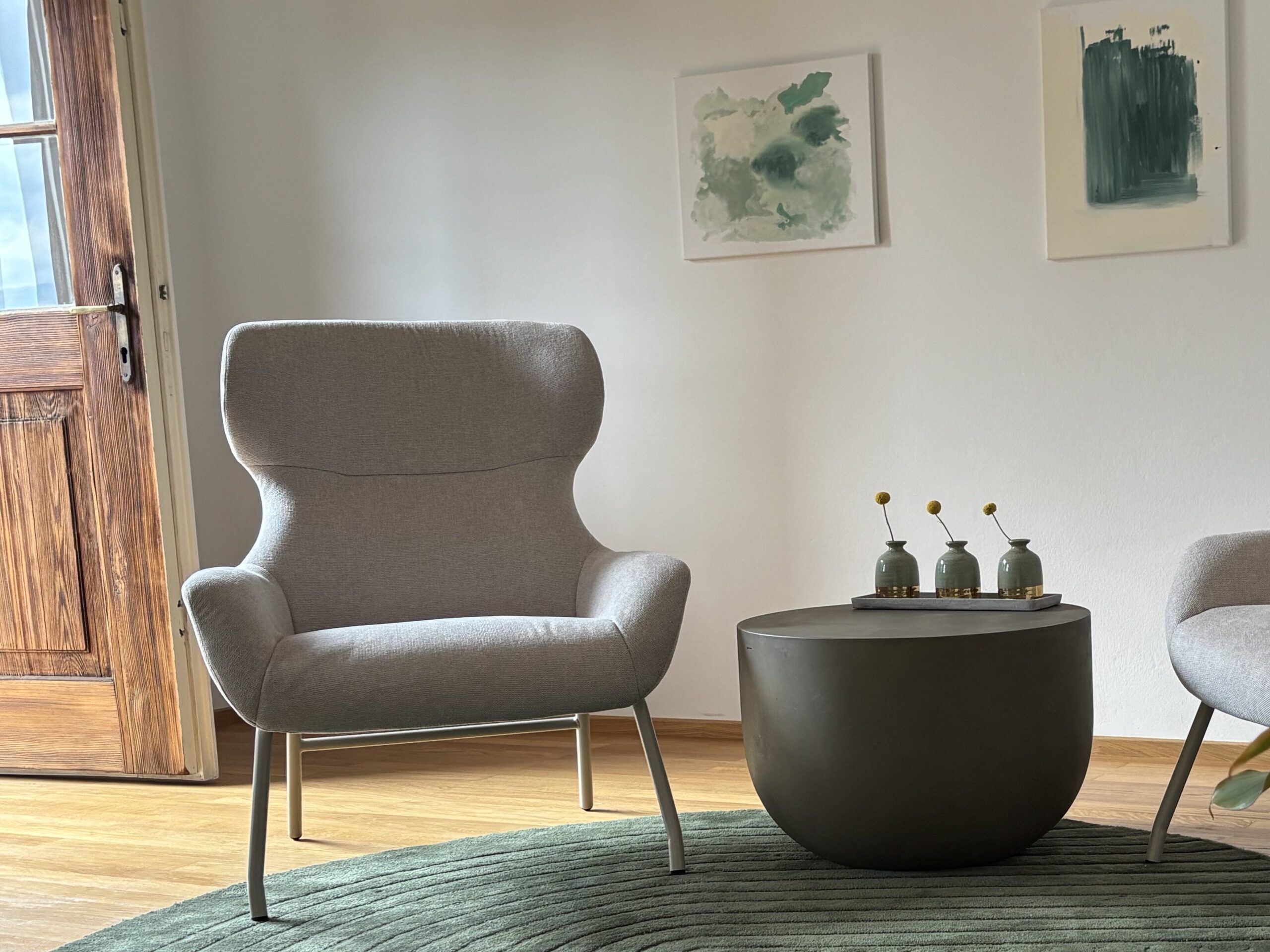 Zwei beige Sessel auf dunkel grünem Teppich