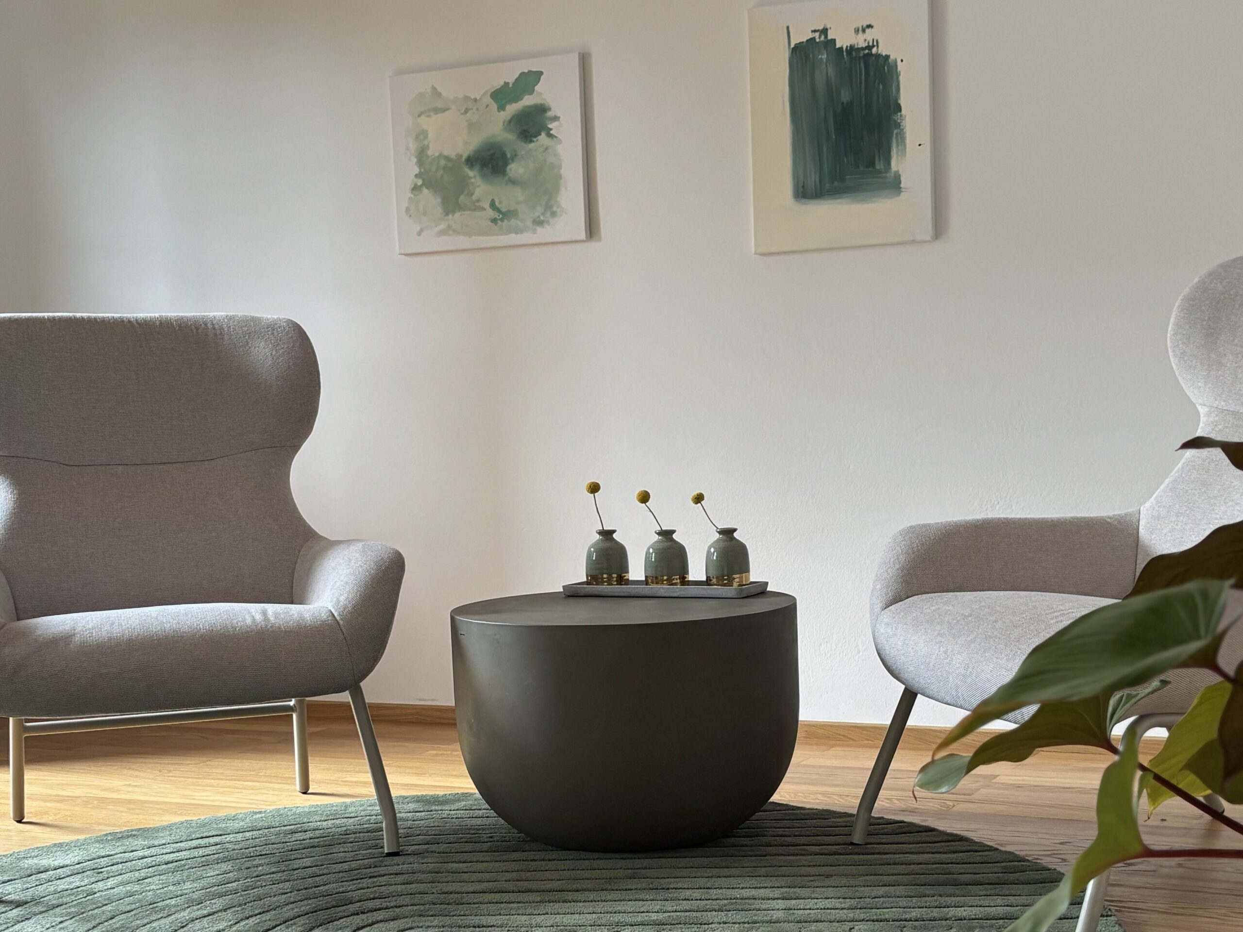 Zwei beige Sessel auf dunkel grünem Teppich