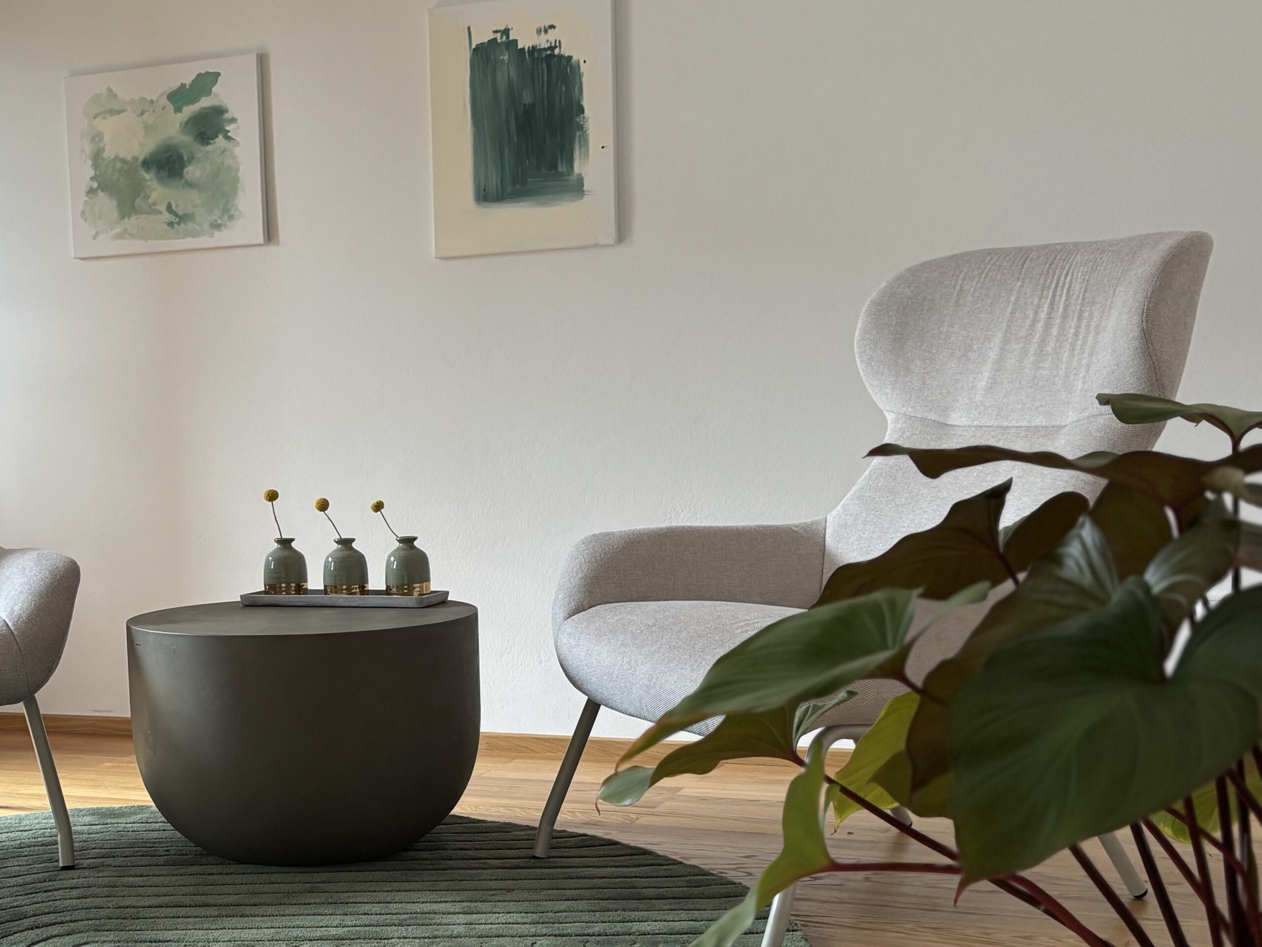 Zwei beige Sessel auf dunkel grünem Teppich